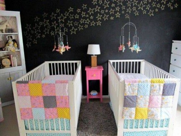 twin-baby-bedrooms-with-stars-wall-decal-and-white-double-cribs-and-colorful-bedding-and-pink-nightstand-and-table-lamp-and-toys