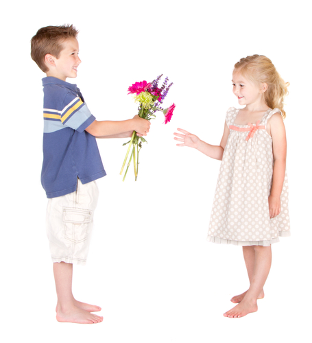 Little boy handing flowers to little girl, isolated on white