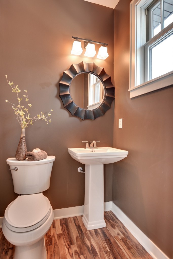 brown-wall-paint-round-mirror-with-frame-wall-lamps-glass-window-panel-washbasin-with-pedestal-stainless-steel-faucet-head-toilet-how-to-decorate-a-bathroom-with-modern-cabinet-1200x1800