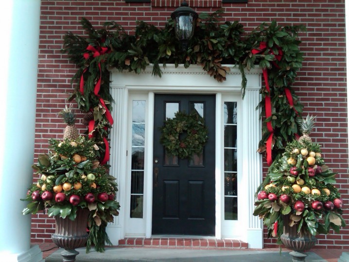 exterior-exposed-red-bricks-wall-and-black-wooden-french-door-mixed-green-plastic-pine-leaves-arrangements-front-porch-christmas-decorations