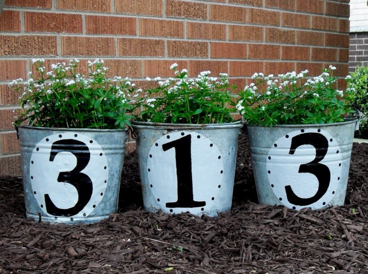 - Use metal buckets as planters, painting them with your house number