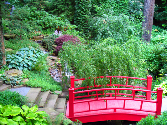 Ornamental oriental garden with walkway and red bridge