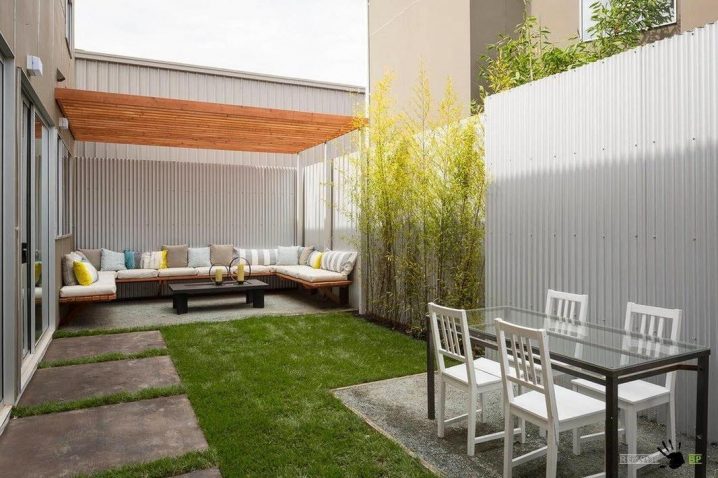 Shady-patio-with-cozy-bench-with-cushions-and-pillows-along-wth-simply-dining-set-decorated-by-plants-and-asbestos-fence-design
