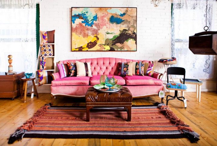 Bright-boho-style-living-room-with-pink-tufted-sofa-and-leather-ottoman-on-a-pretty-rug-completed-by-assorted-pillows-and-big-painting-on-white-brick-wall-also-sheer-curatin-idea