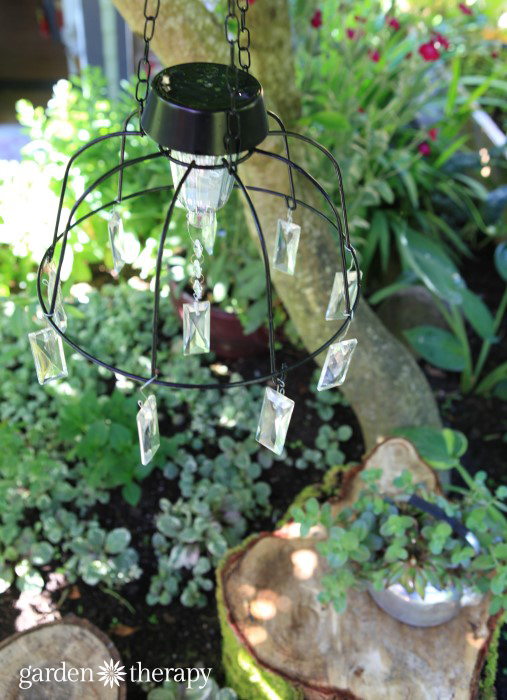 DIY-Solar-Light-Chandelier-hanging-over-rustic-tree-stump-table-and-chairs